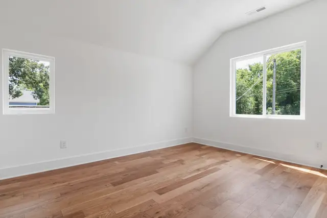 Quiet empty room with white walls and windows looking onto green trees